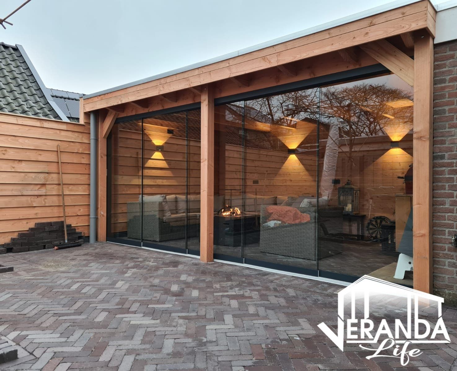 Een houten gebouw met glazen schuifdeuren en een stenen patio.