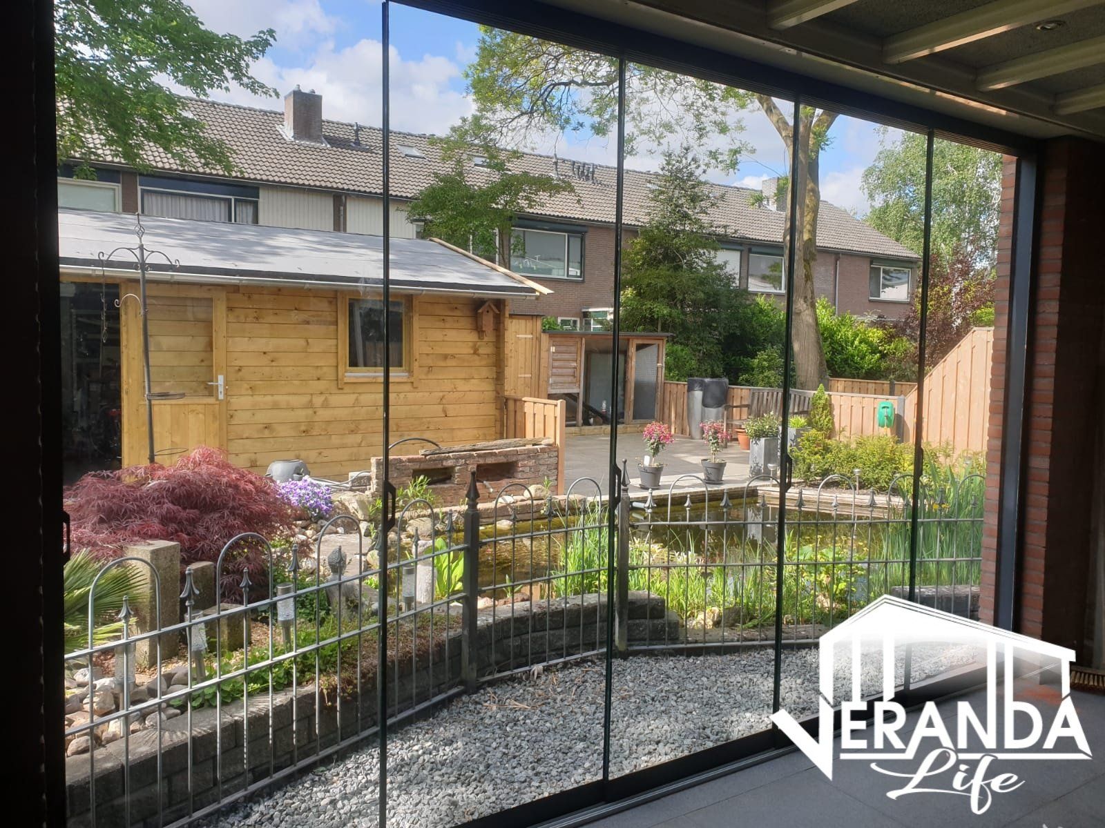 Een patio met glazen schuifdeuren die leiden naar een tuin en een huis.