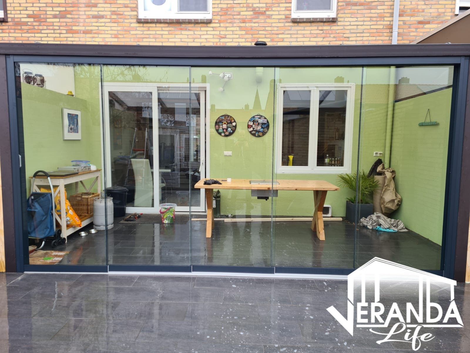 Een patio met glazen schuifdeuren en een houten tafel.