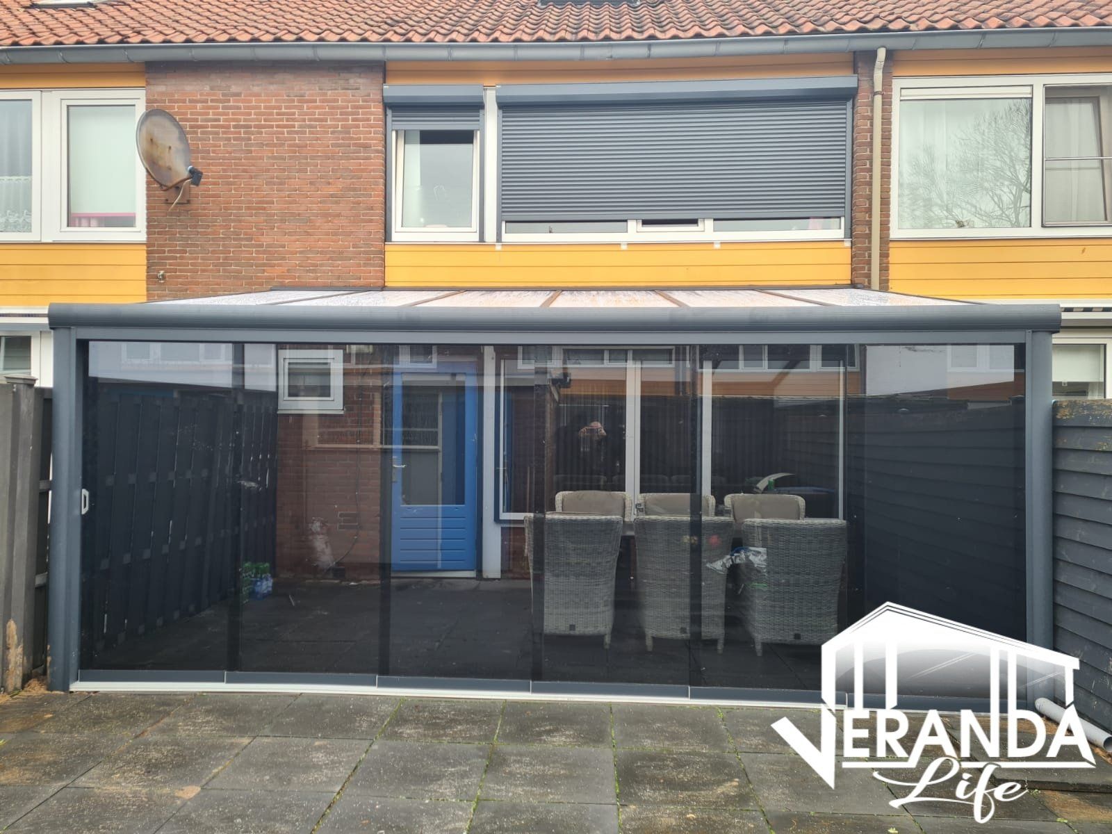 Een huis met een patio met glazen schuifdeuren en een dak.