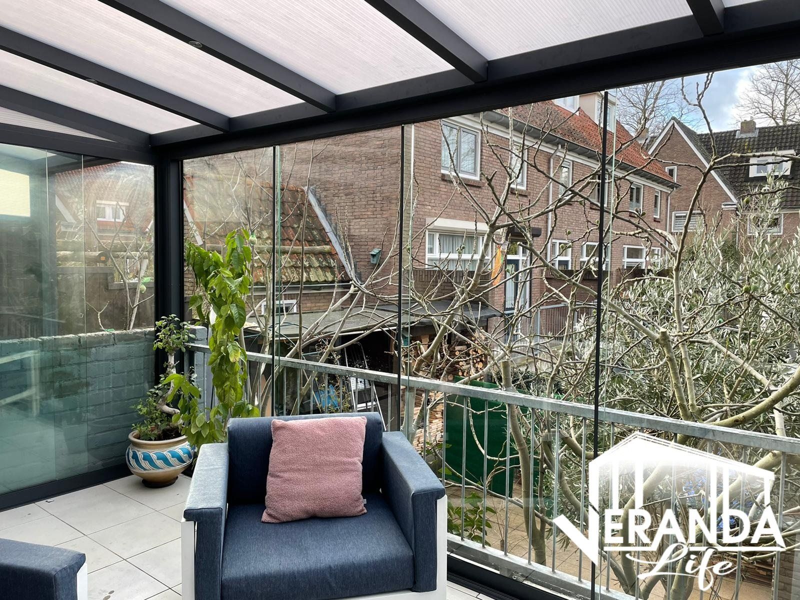 Een woonkamer met een stoel en een tafel met uitzicht op een huis.