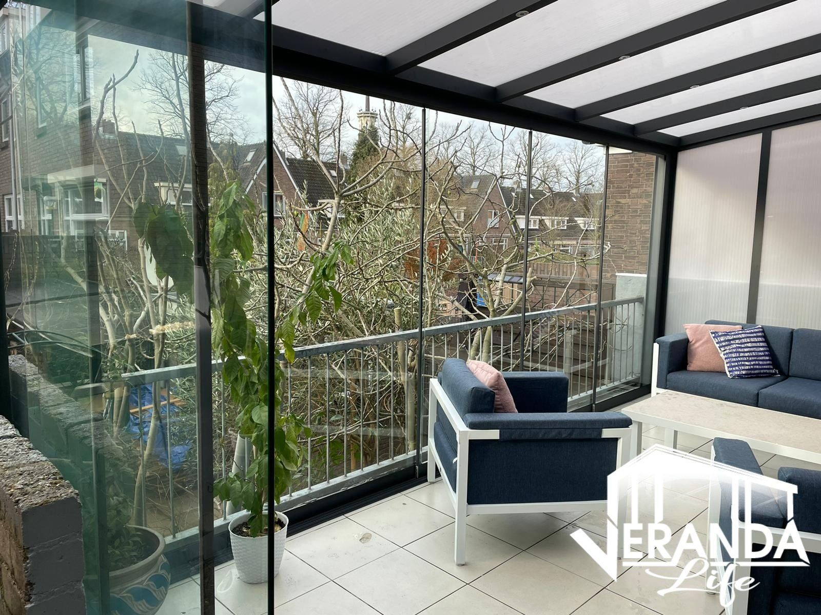 Een woonkamer met een bank, stoel, tafel en potplant.