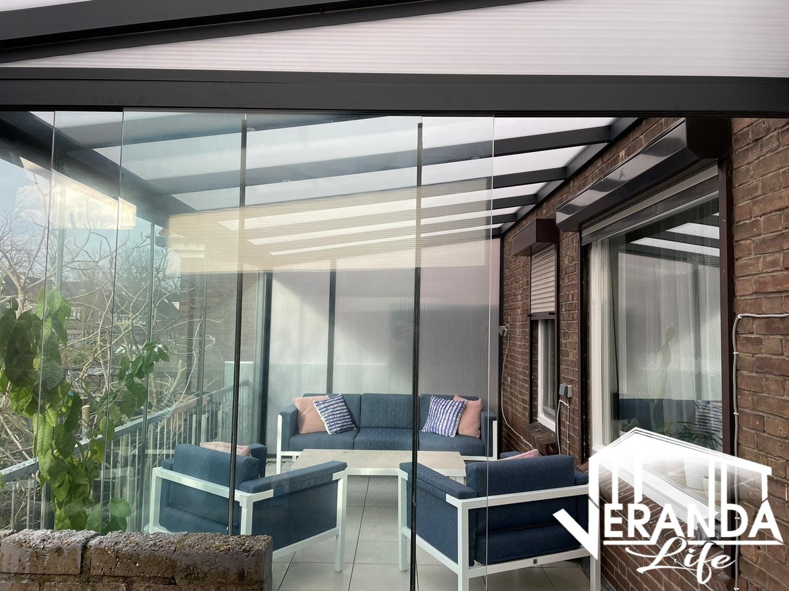 Een woonkamer met een bank en stoelen onder een glazen dak.