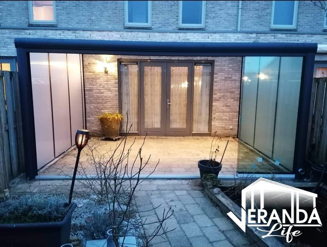 Een patio met glazen schuifdeuren en een bakstenen gebouw op de achtergrond.