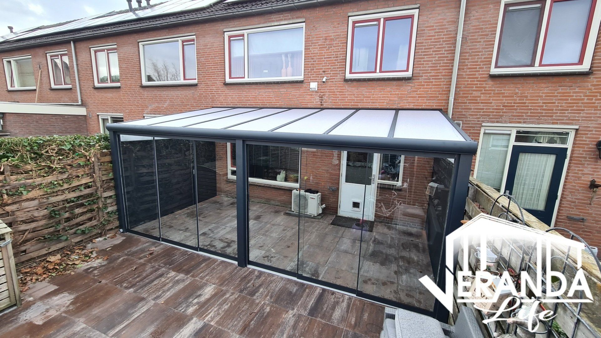 Een bakstenen huis met een overdekt terras ervoor.