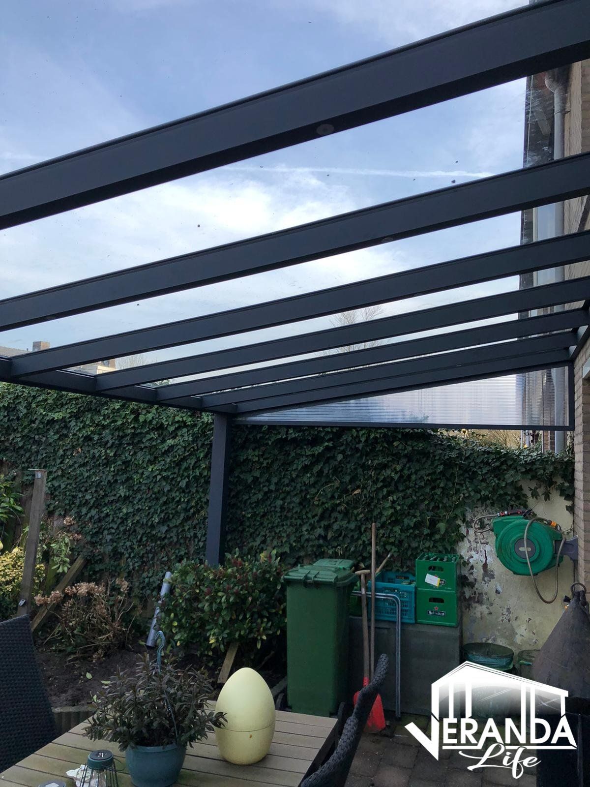 Een patio met een tafel en stoelen onder een helder dak.