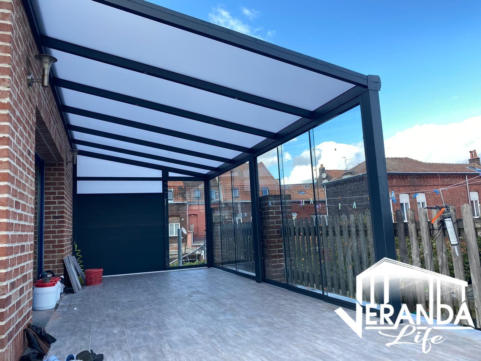 Een patio met een overkapping erboven en een bakstenen gebouw op de achtergrond.