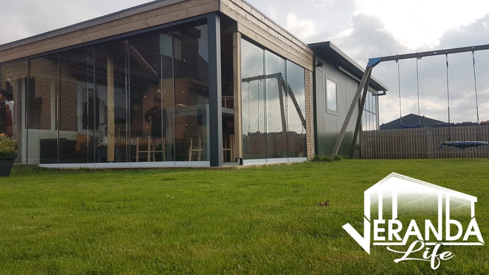 Een huis met veel ramen staat op een weelderig groen gazon.