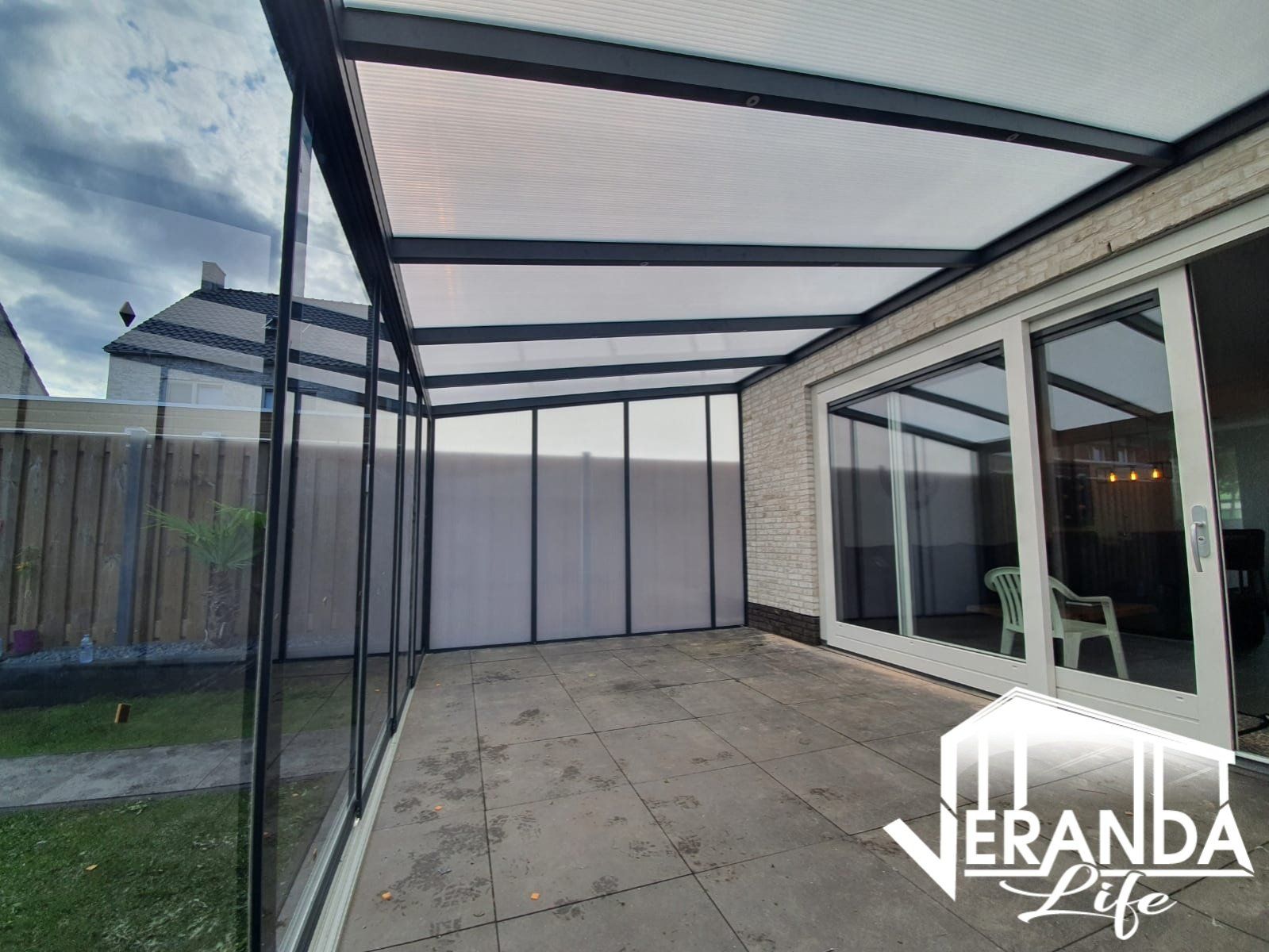 Een patio met glazen schuifdeuren en een helder dak