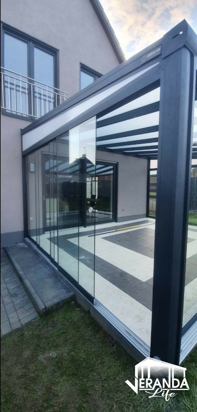 Aan de zijkant van een huis staat een pergola met glazen schuifdeuren.