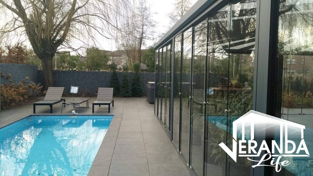 Een groot zwembad is omgeven door een glazen gebouw.