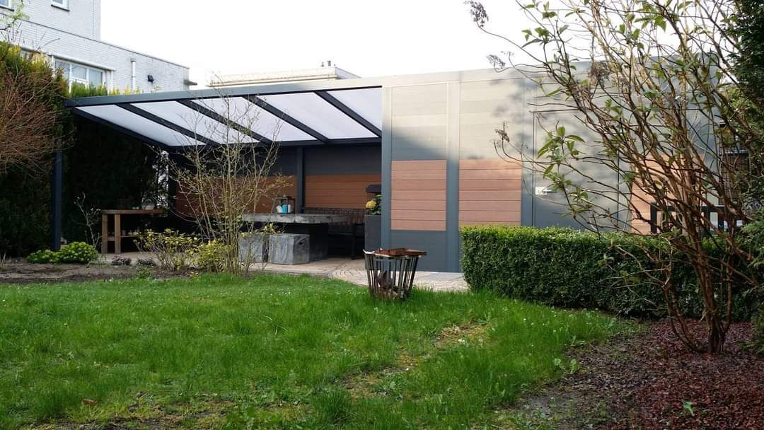 Een achtertuin met een pergola en een tafel in het midden.