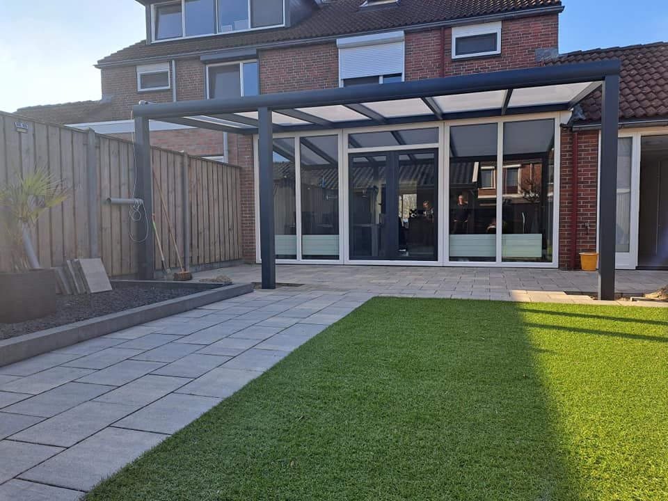 Een huis met een terras en een pergola in de achtertuin.