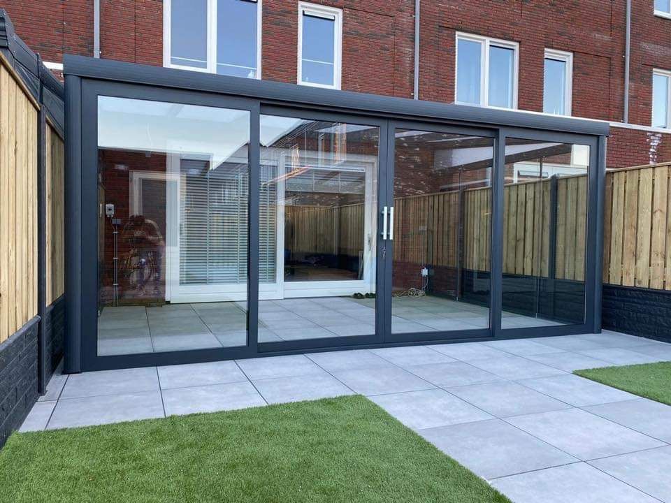 Een patio met glazen schuifdeuren en een bakstenen gebouw op de achtergrond.