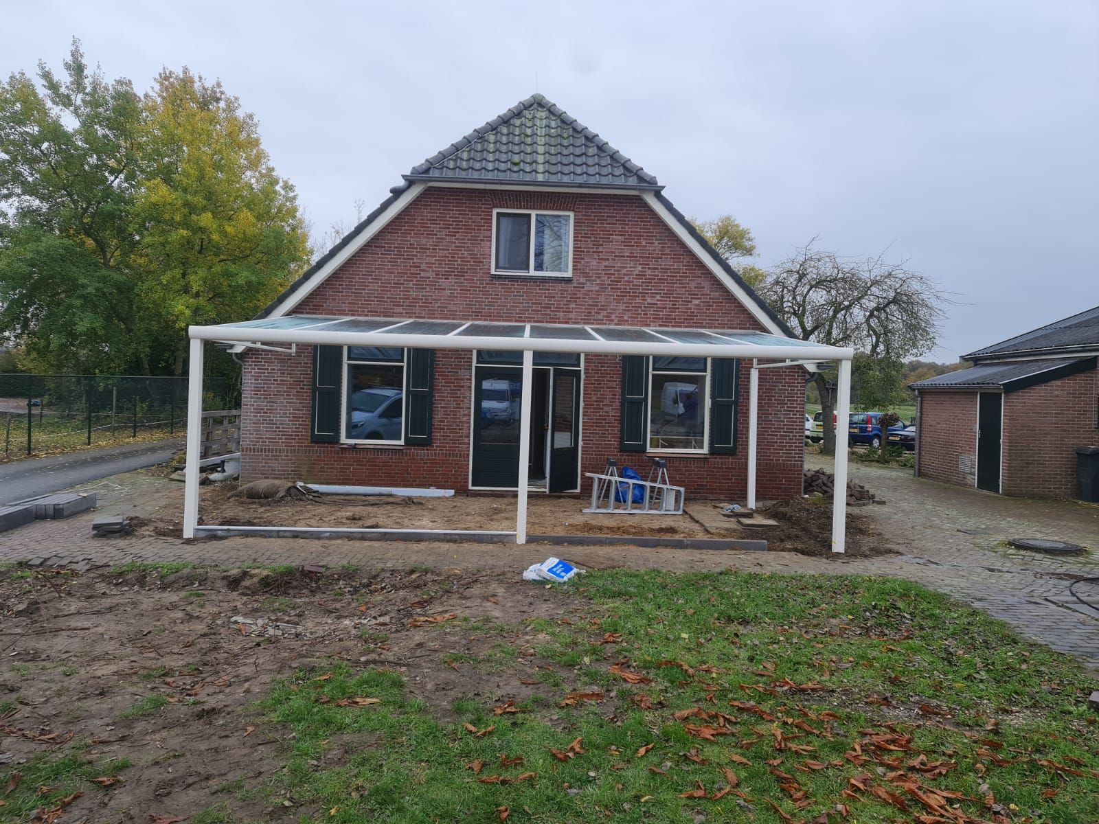 Een bakstenen huis met een witte veranda ervoor.
