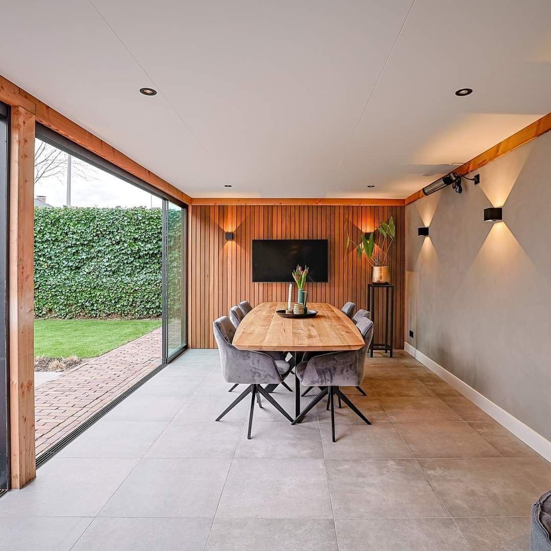 Een eetkamer met een houten tafel en stoelen en een flatscreen-tv.