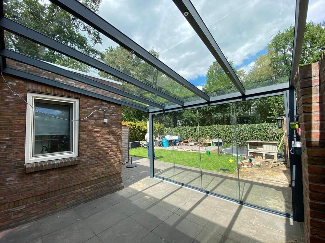 Een patio met een glazen dak en een bakstenen gebouw op de achtergrond.