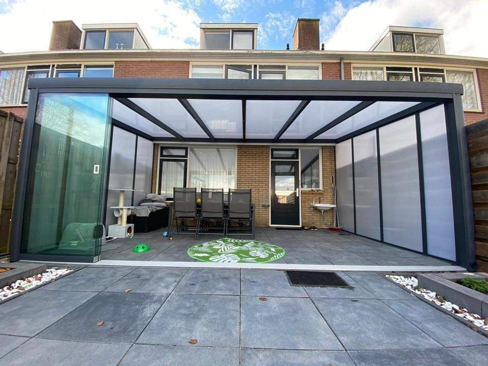 Een patio met pergola en stoelen voor een huis.