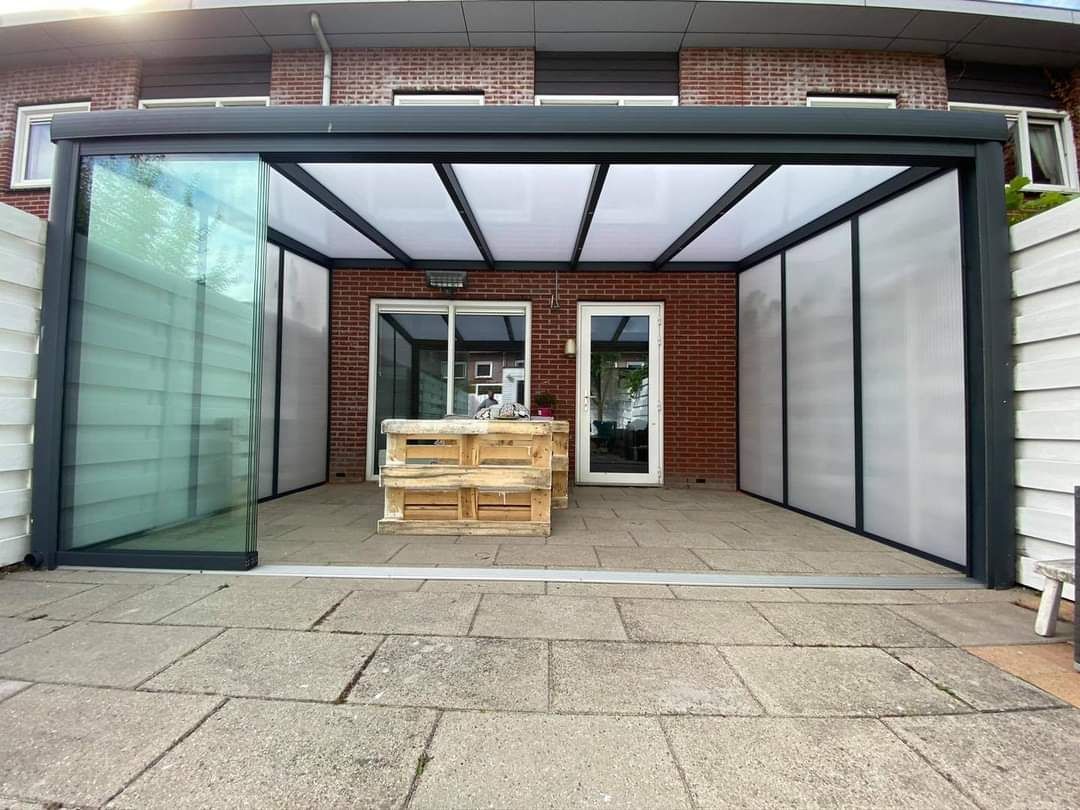 Een patio met een glazen schuifdeur en een tafel en stoelen onder een baldakijn.