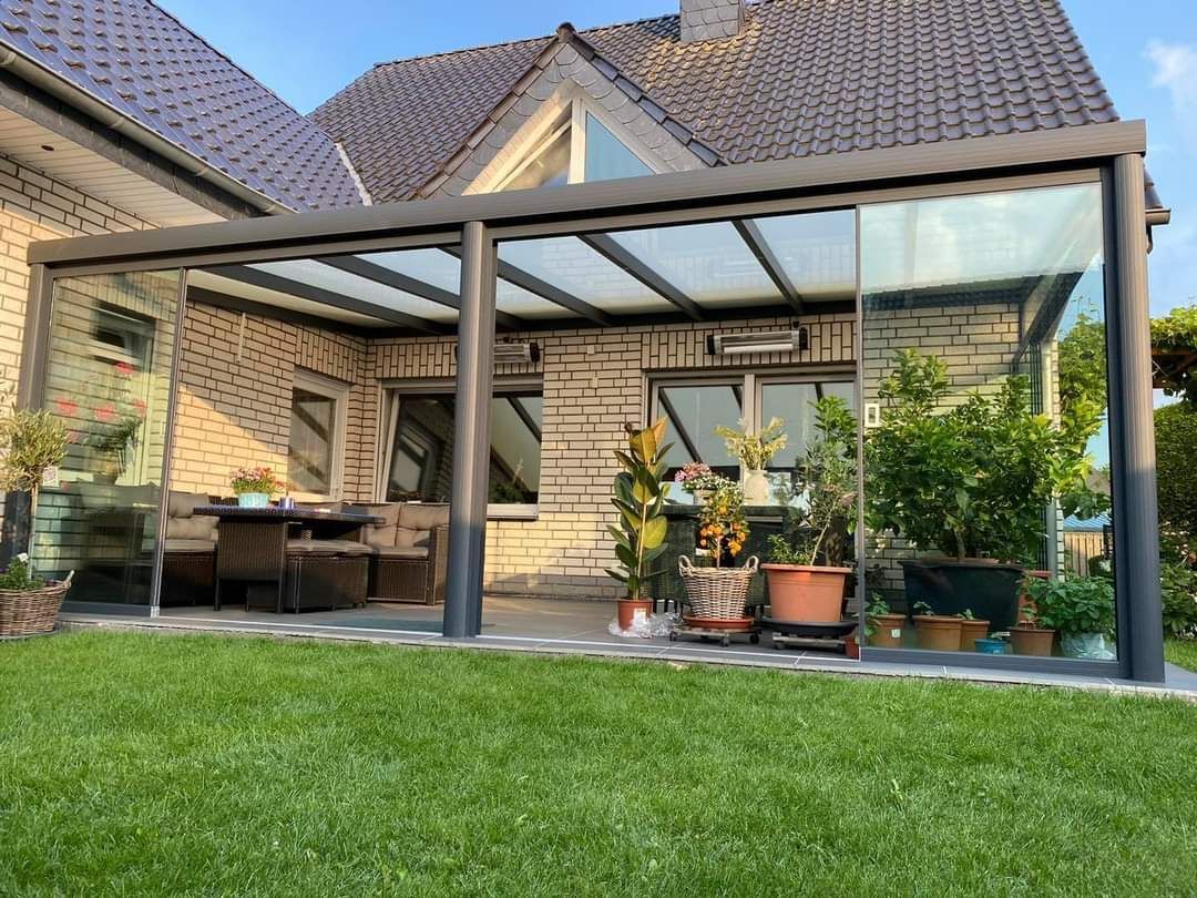 Een woning met een overdekt terras met glazen schuifdeuren in de achtertuin.