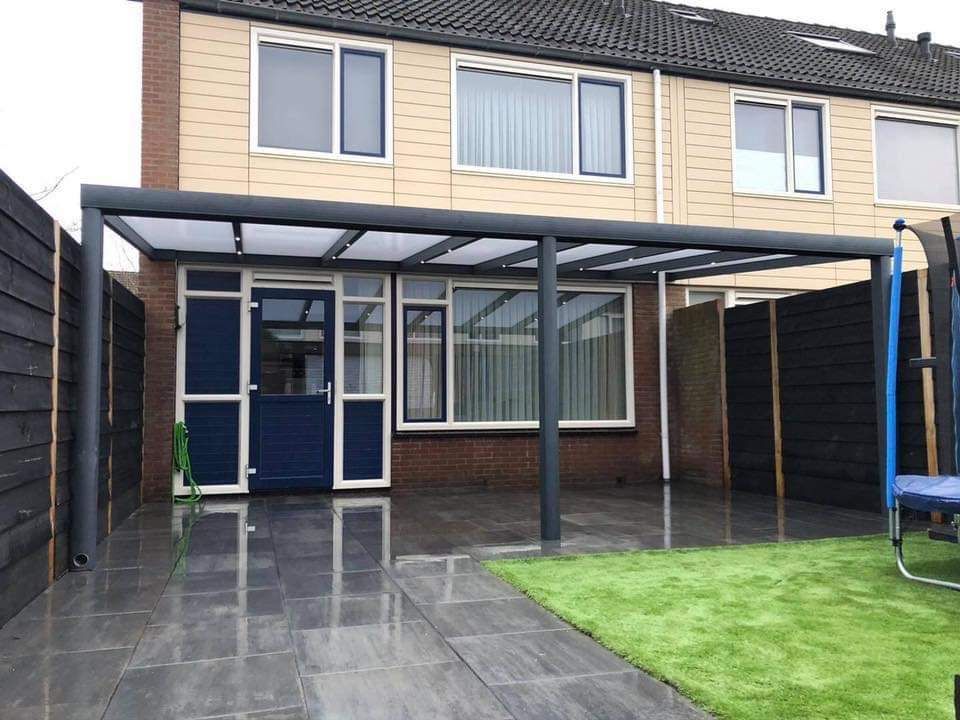Een huis met een terras en een pergola ervoor.