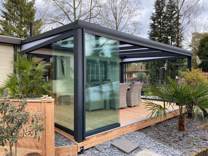 Een patio met een glazen dak en glazen schuifdeuren.