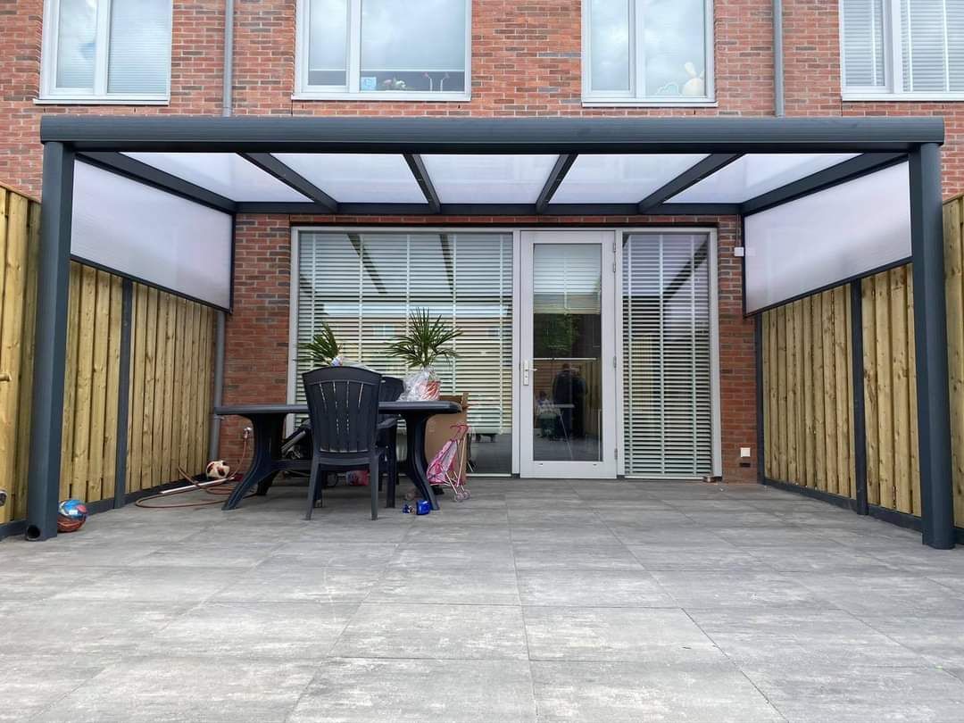 Een terras met een tafel en stoelen onder een baldakijn.