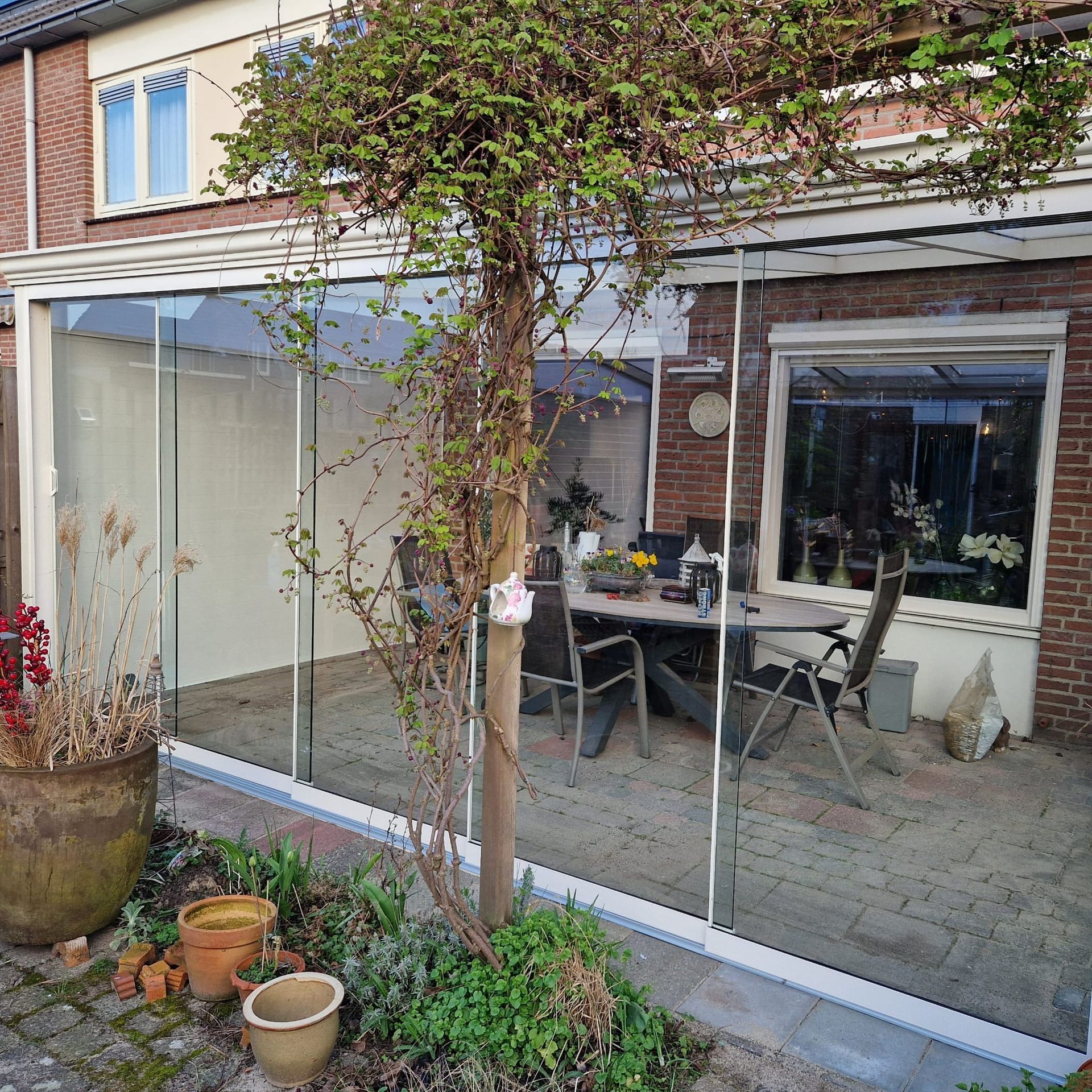 Een patio met een tafel en stoelen en een boom ervoor