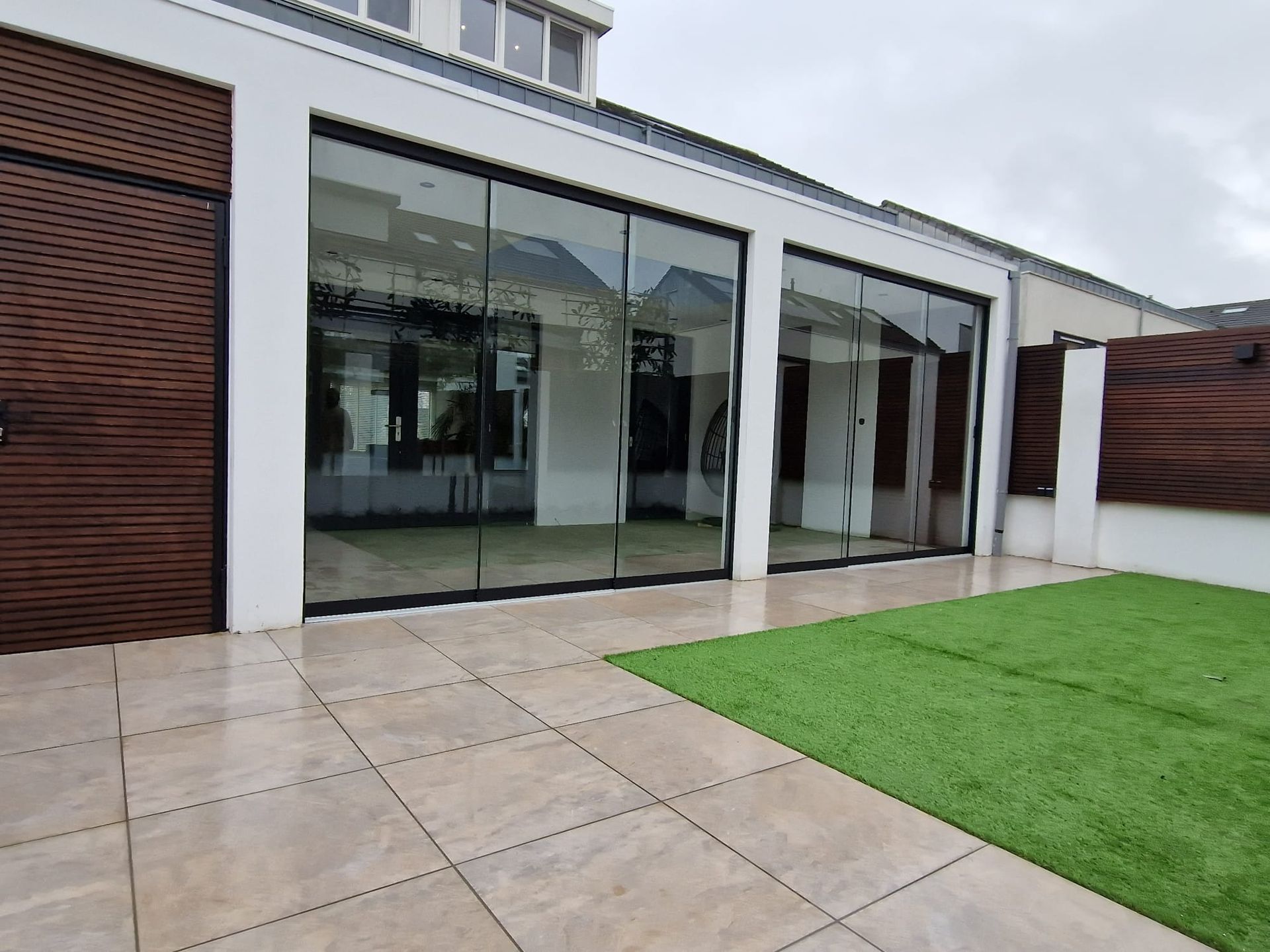 Een huis met veel ramen en een grasveld ervoor