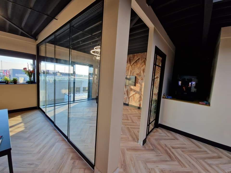 Een kamer met veel ramen en een houten vloer.