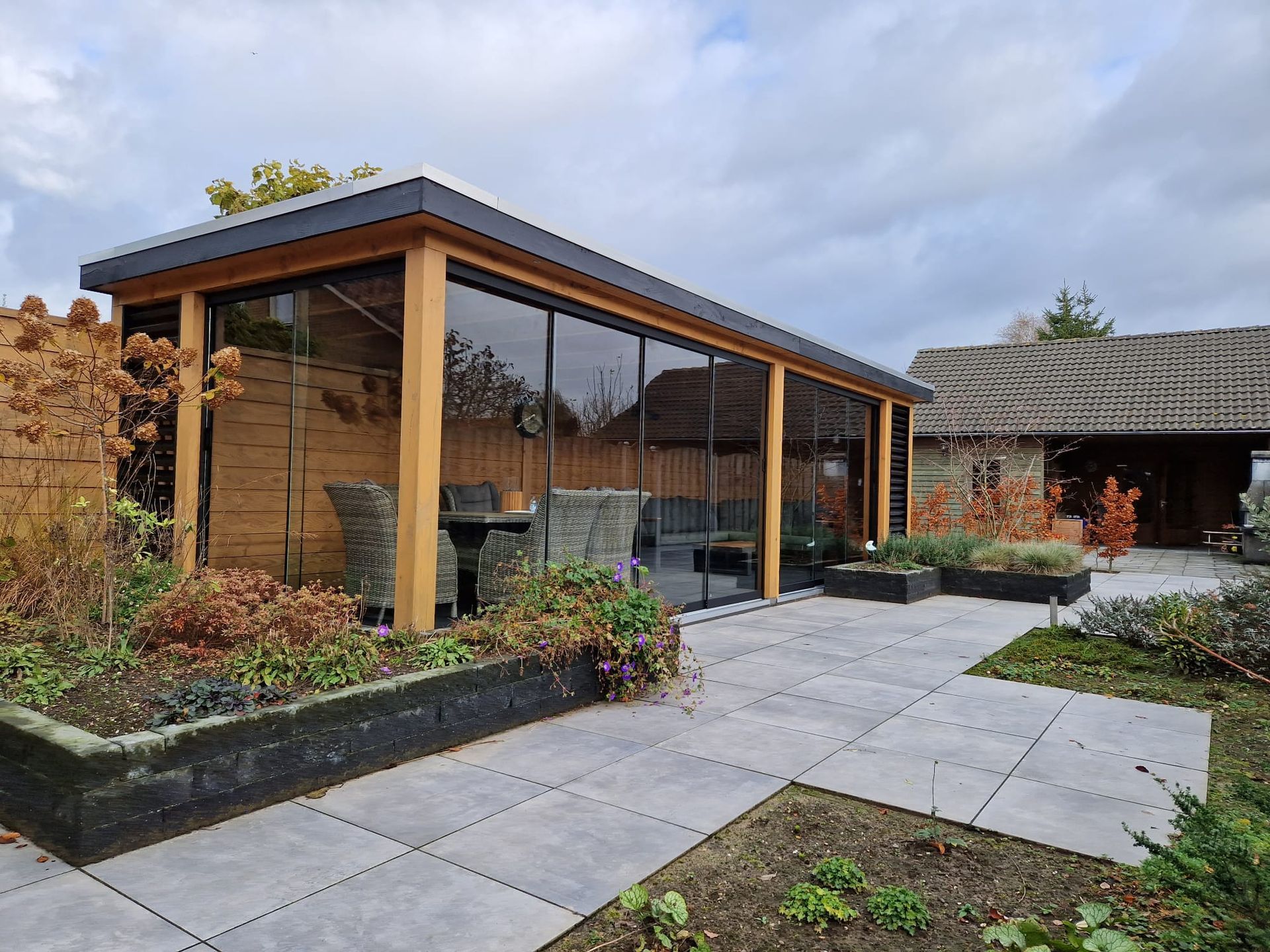 Een groot houten gebouw met veel ramen en een patio ervoor.