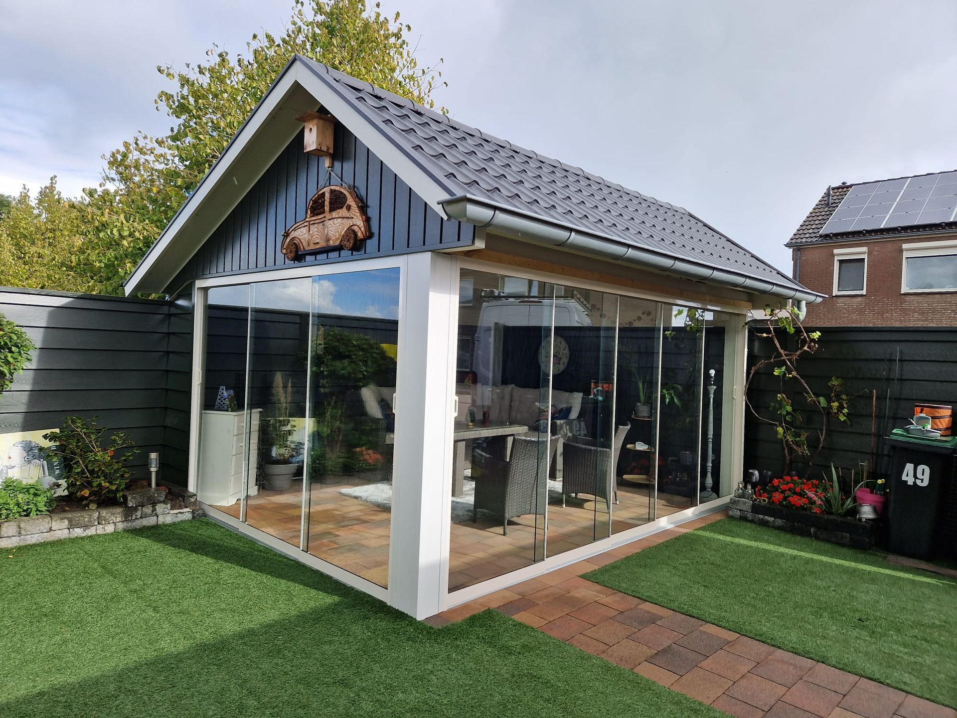 Een klein huis met een glazen schuifdeur in de achtertuin.