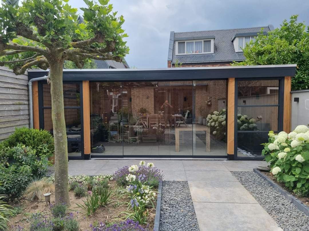 Midden in een tuin staat een groot gebouw met veel ramen.