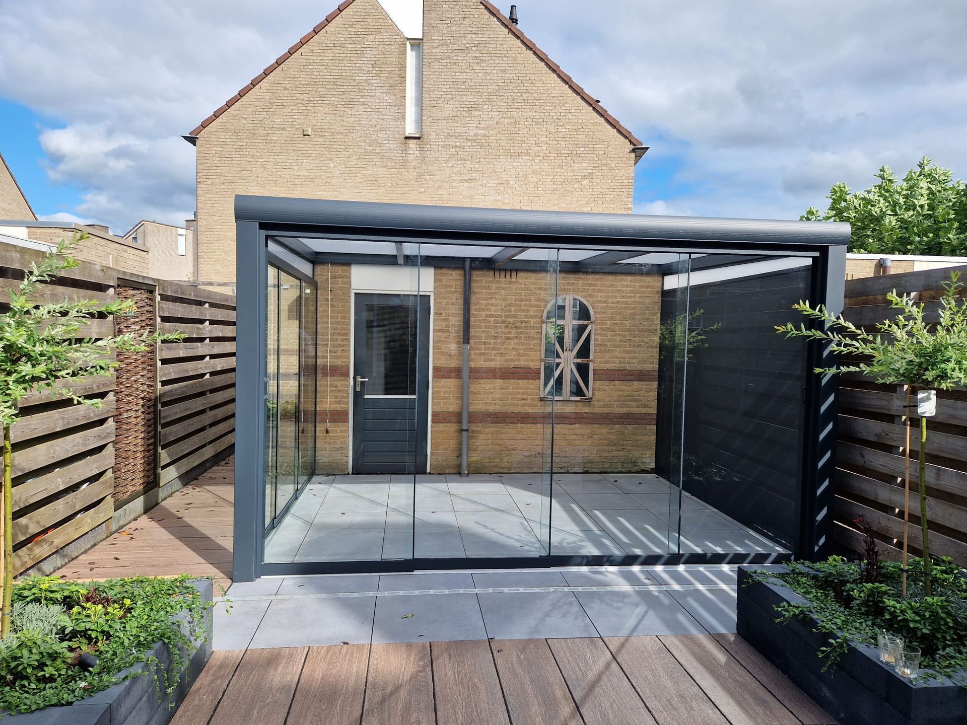 Een bakstenen huis met een glazen patio ervoor.