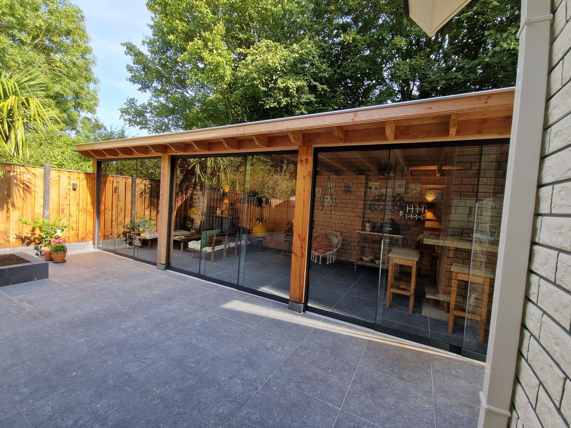 Een patio met glazen schuifdeuren en een houten dak.