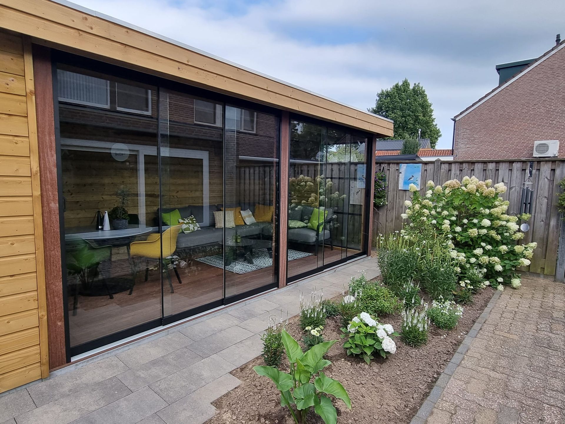 Een huis met veel ramen en een tuin ervoor.