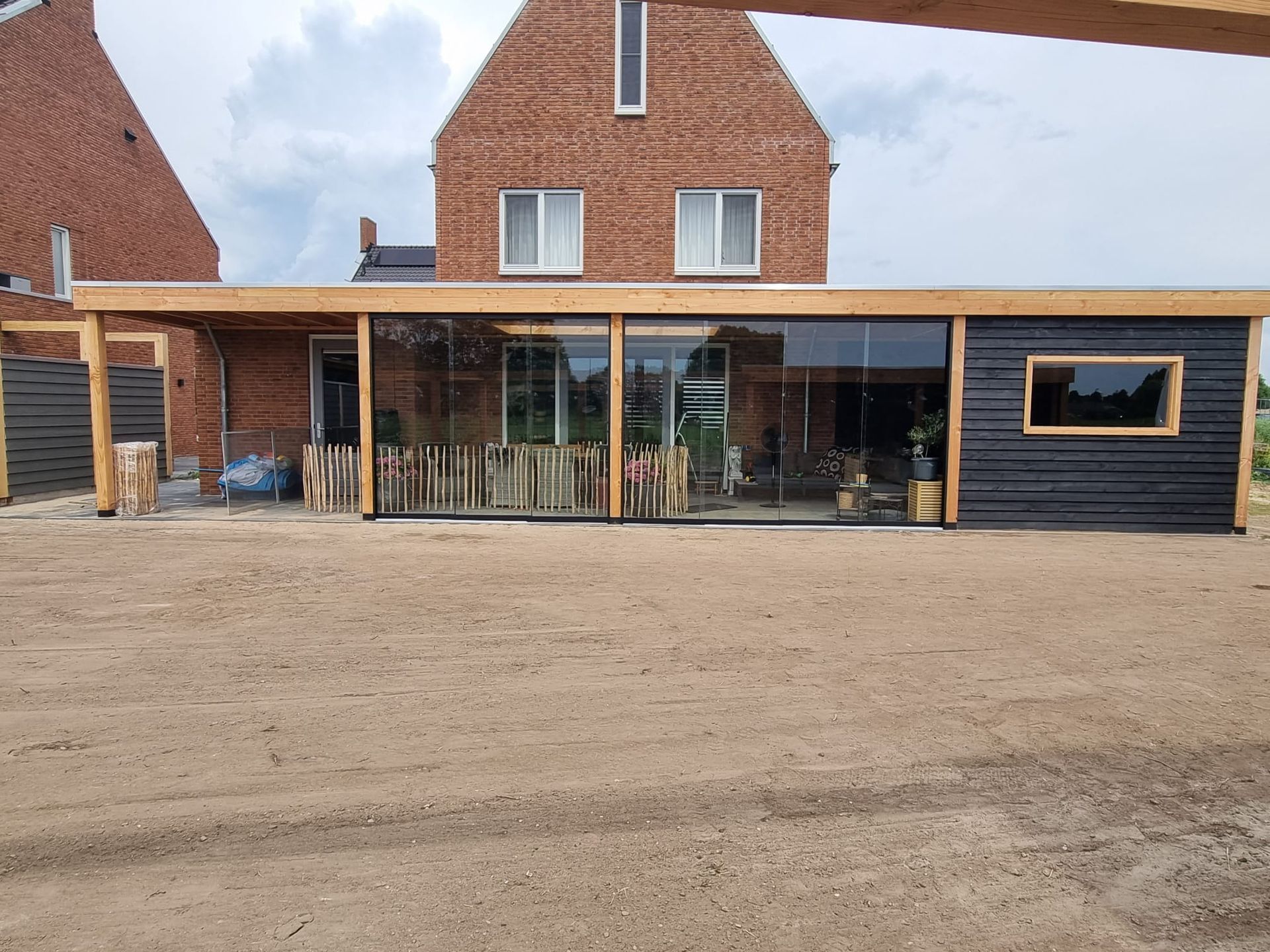 Een bakstenen huis met een houten constructie ervoor