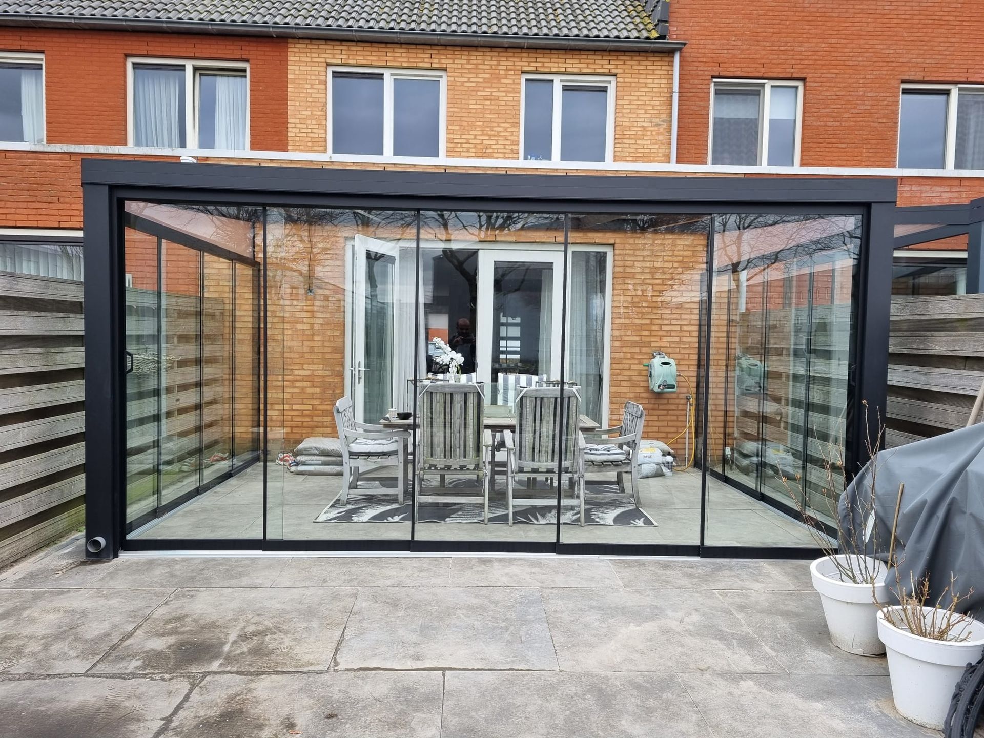 Een patio met een tafel en stoelen onder een glazen dak.