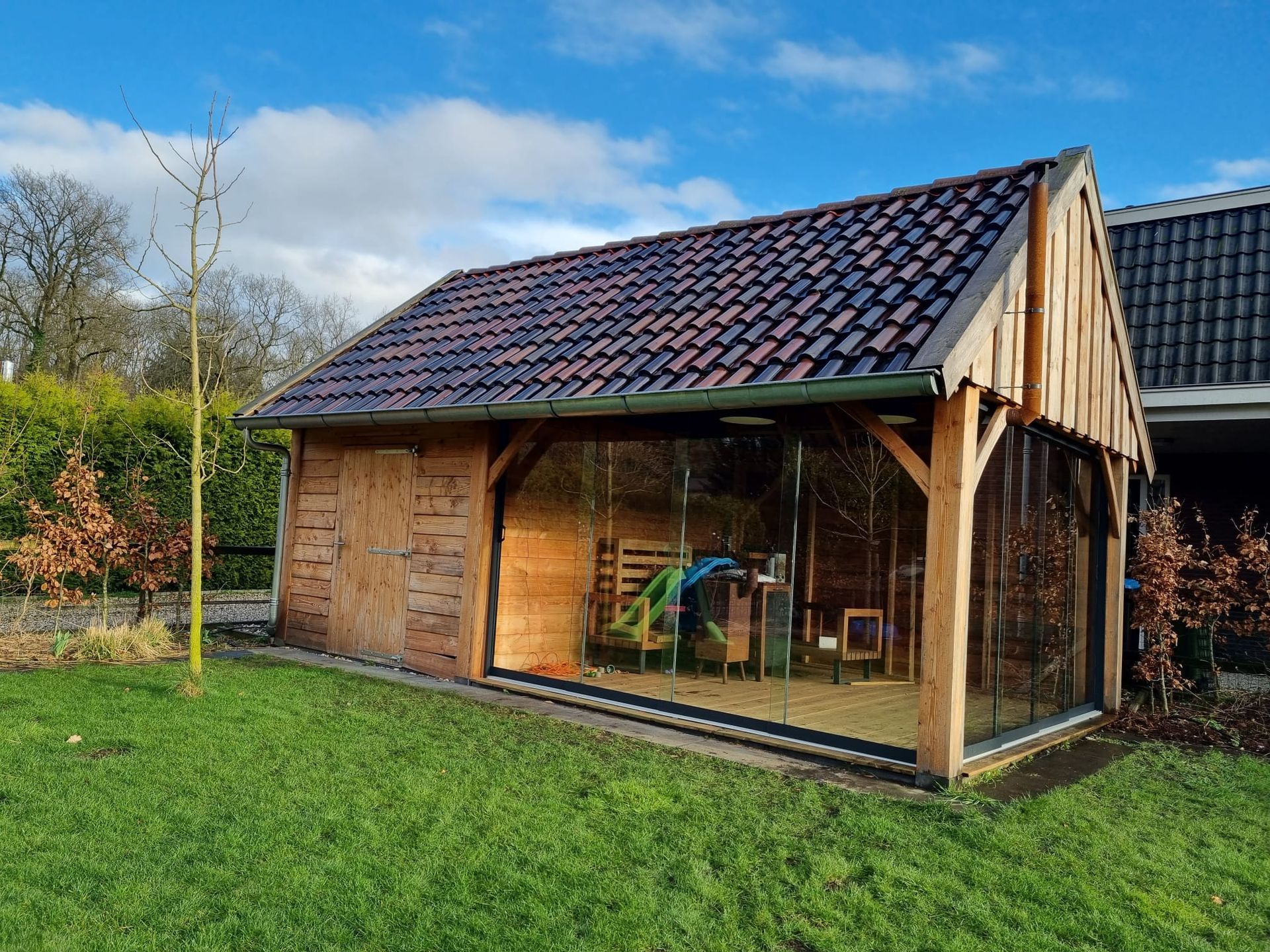 Midden in een weelderig groen veld staat een houten gebouw met een pannendak.