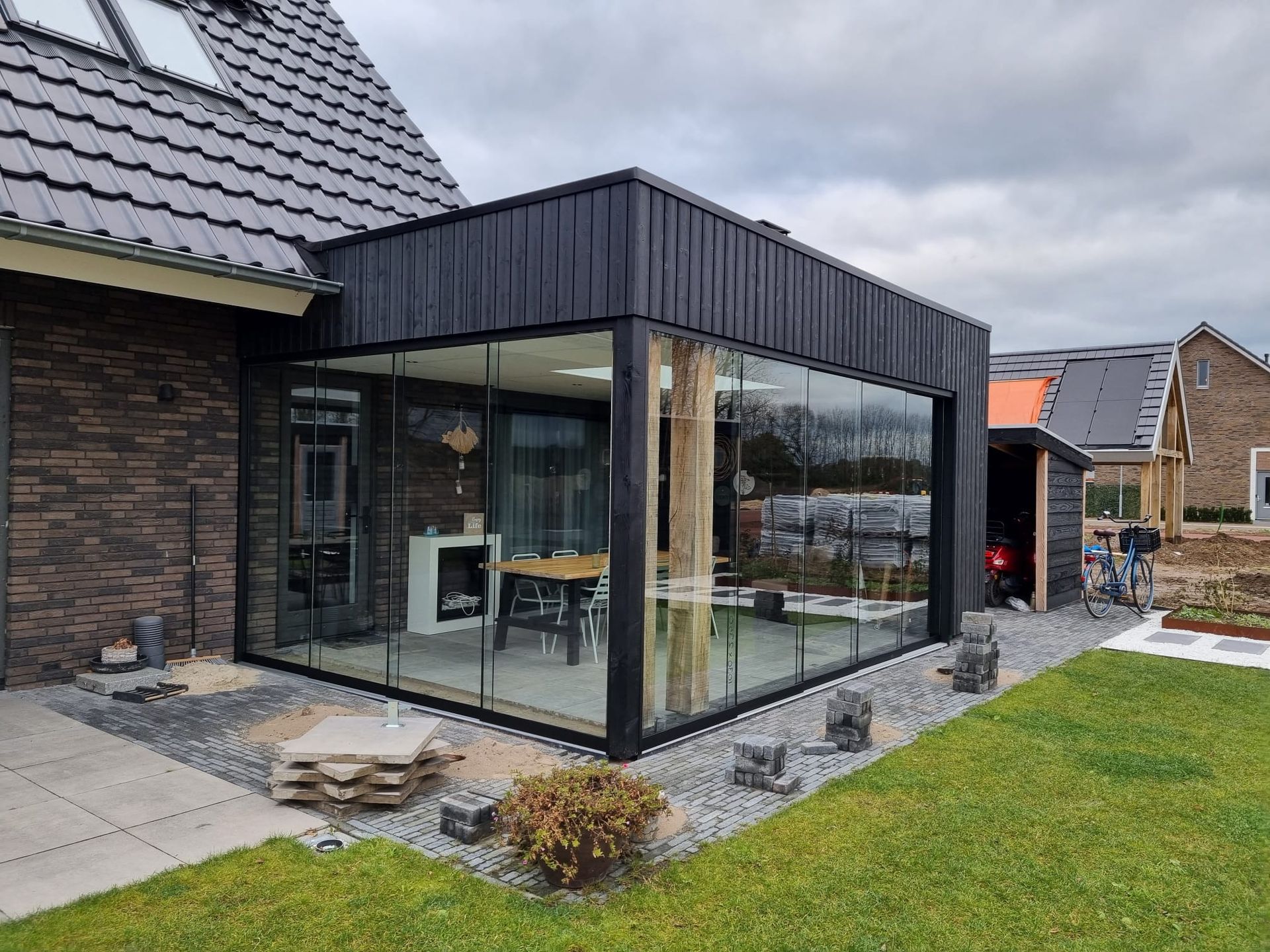 Een bakstenen huis met een grote glazen patio ervoor.