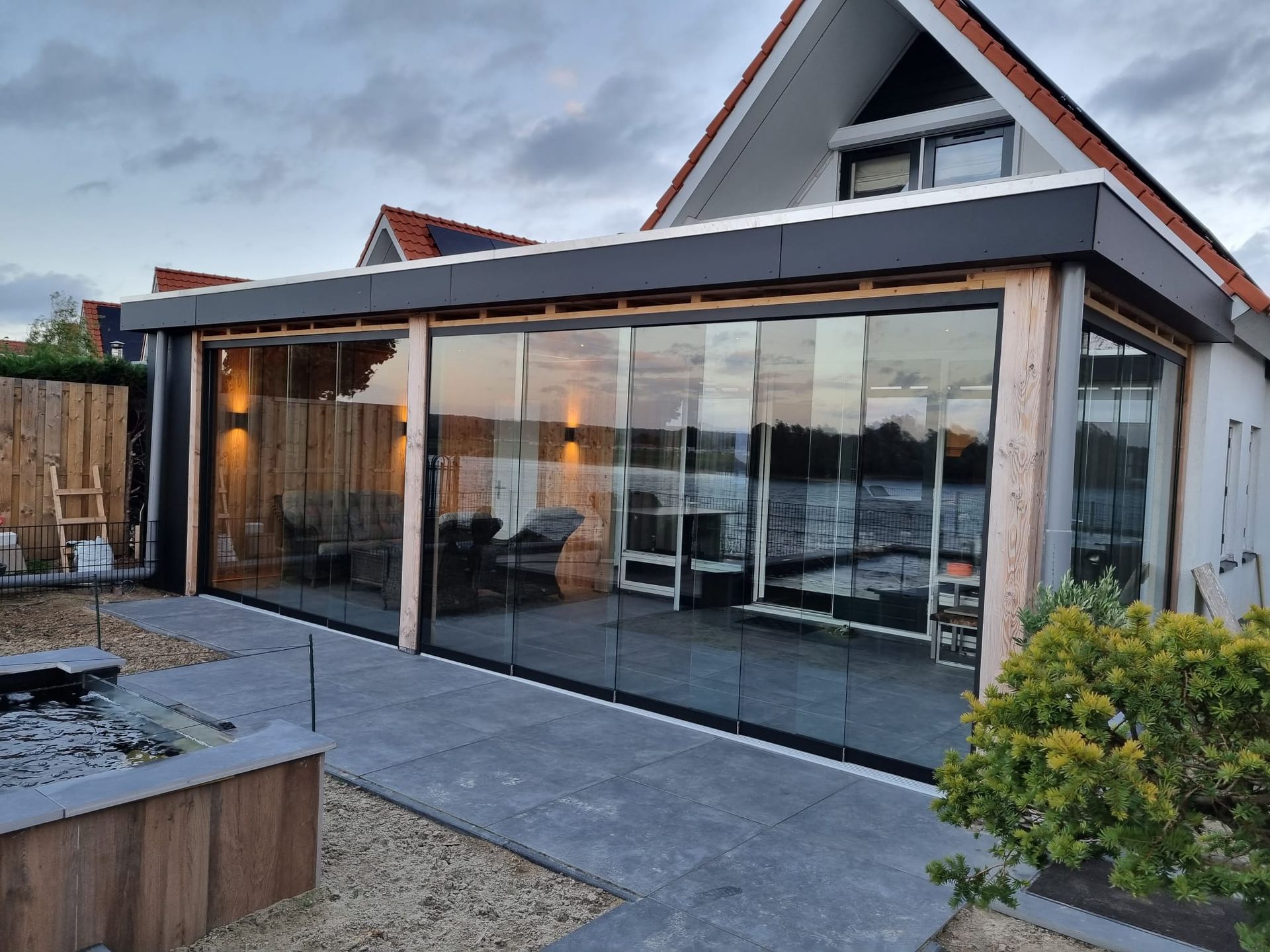 Een huis met een grote glazen wand en glazen schuifdeuren.