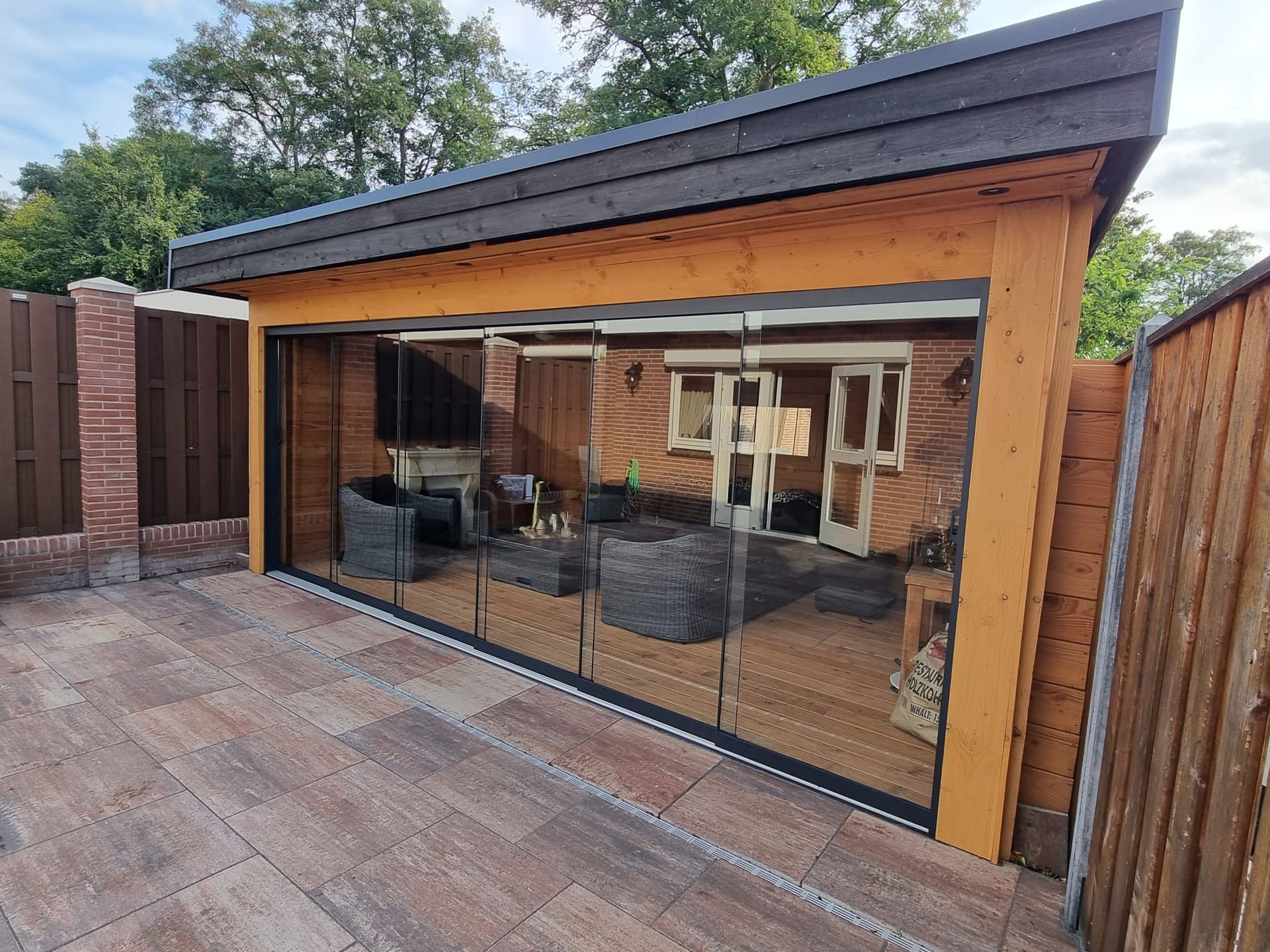 Een houten gebouw met glazen schuifdeuren en een patio ervoor.