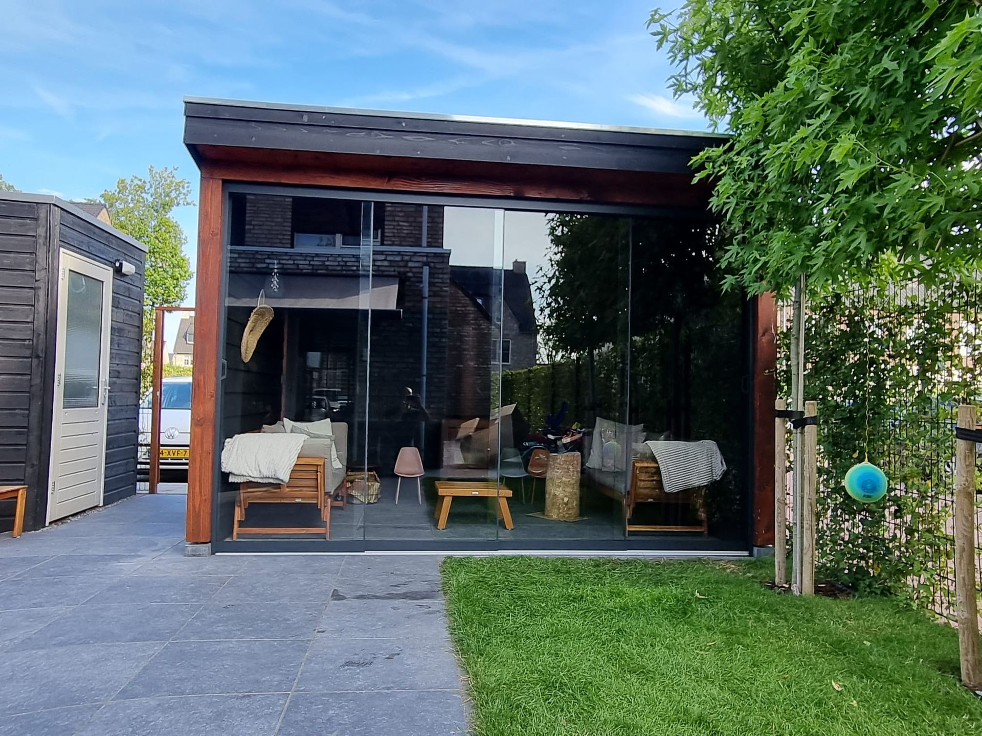 Een klein huis met veel ramen en meubels in de achtertuin.