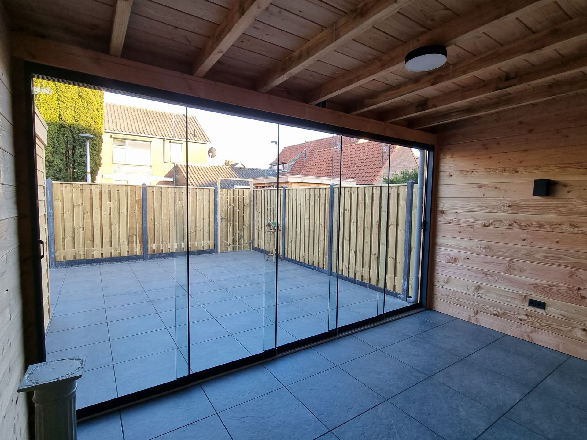 Een houten gebouw met glazen schuifdeuren die naar een patio leiden.