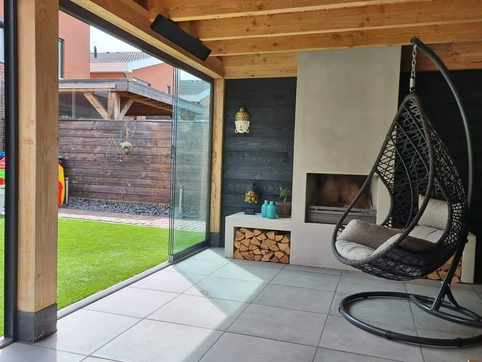 Een terras met twee hangstoelen en een open haard.