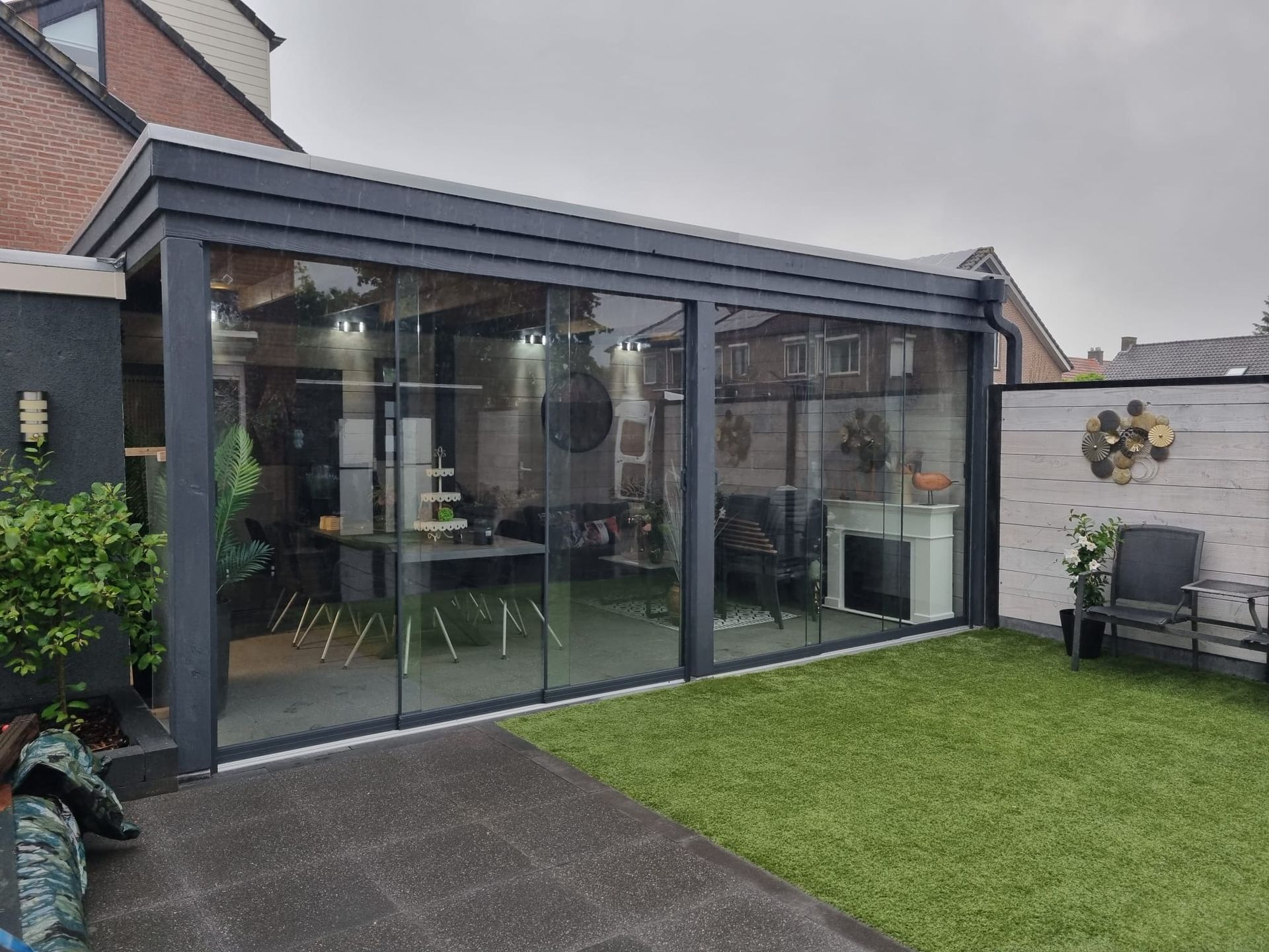 Een grote glazen kamer met glazen schuifdeuren in een achtertuin.