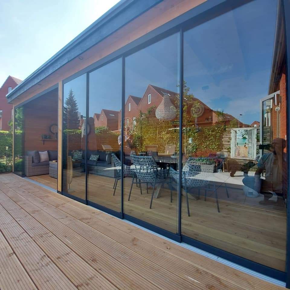 Een huis met veel ramen en een houten terras