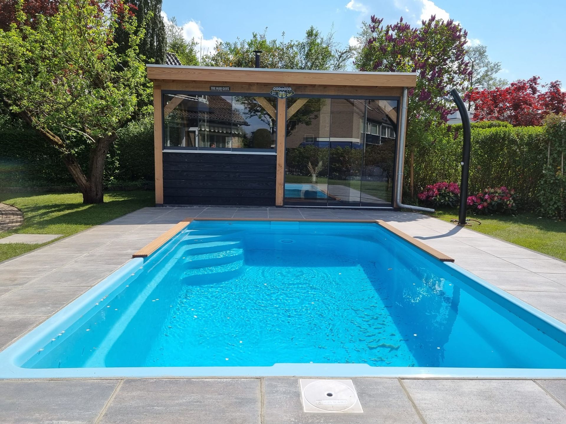 Een zwembad met een tuinhuisje op de achtergrond