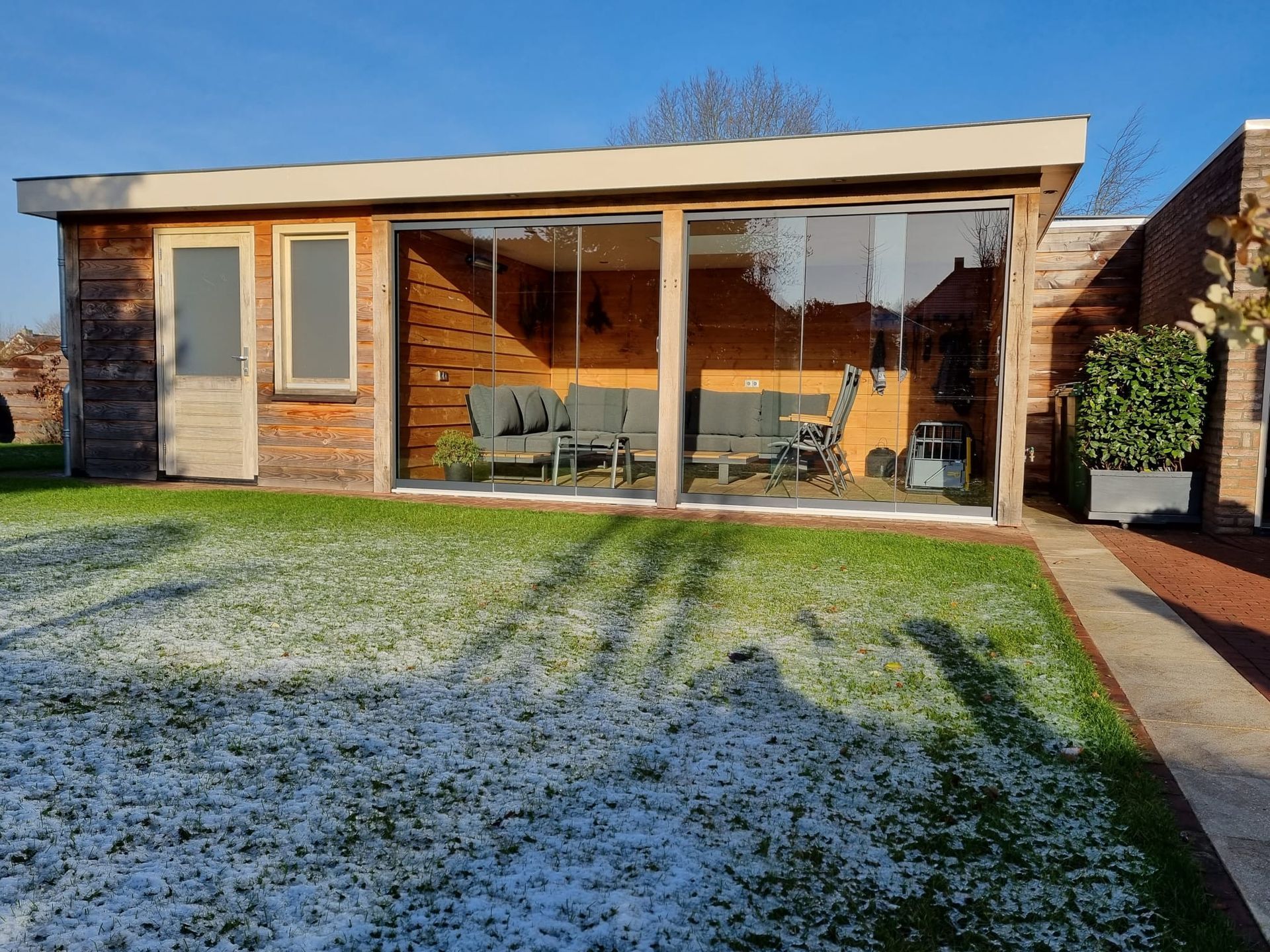 Een huis met veel ramen en een bank in de achtertuin