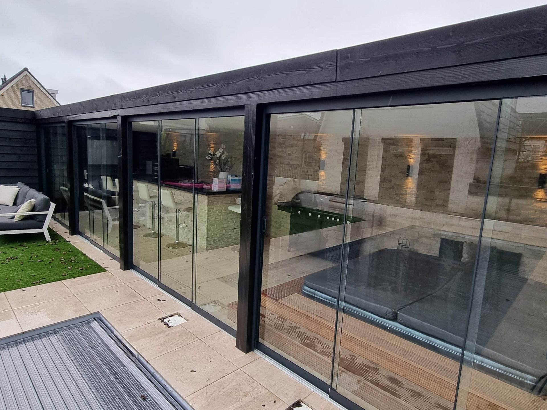 Een huis met veel ramen en glazen schuifdeuren.